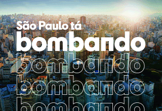 Imagem animada mostrando uma vista aérea da cidade de São Paulo, com vários prédios iluminados pelo sol. Em destaque, aparece o texto em letras grandes e brancas: São Paulo tá bombando, acompanhado de uma bandeira da cidade