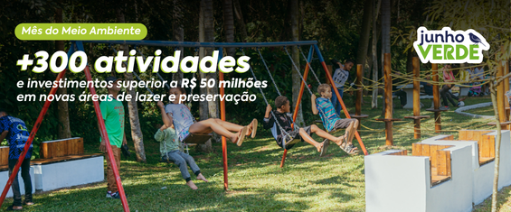 Banner horizontal colorido do Junho Verde, mês dedicado ao meio ambiente. Ao fundo, há uma área verde de parque com gramado e árvores de tons verde-escuro. Em primeiro plano, crianças brincam em balanços de estrutura metálica azul e vermelha, demonstrando diversão e convivência ao ar livre. À direita, aparecem bancos e elementos de madeira em tons amadeirados e brancos, compondo o espaço de lazer.  No canto superior esquerdo, há um selo verde-claro com o texto “Mês do Meio Ambiente”. Logo abaixo, em letras grandes brancas, destaca-se a mensagem: “+300 atividades”, seguida do texto em branco: “e investimentos superiores a R$ 50 milhões em novas áreas de lazer e preservação”. No canto superior direito está a marca “Junho Verde”, nas cores verde, azul e branco, acompanhada da ilustração de uma ave. A imagem utiliza predominantemente tons de verde, azul, branco, marrom e vermelho, reforçando a temática ambiental e de contato com a natureza.