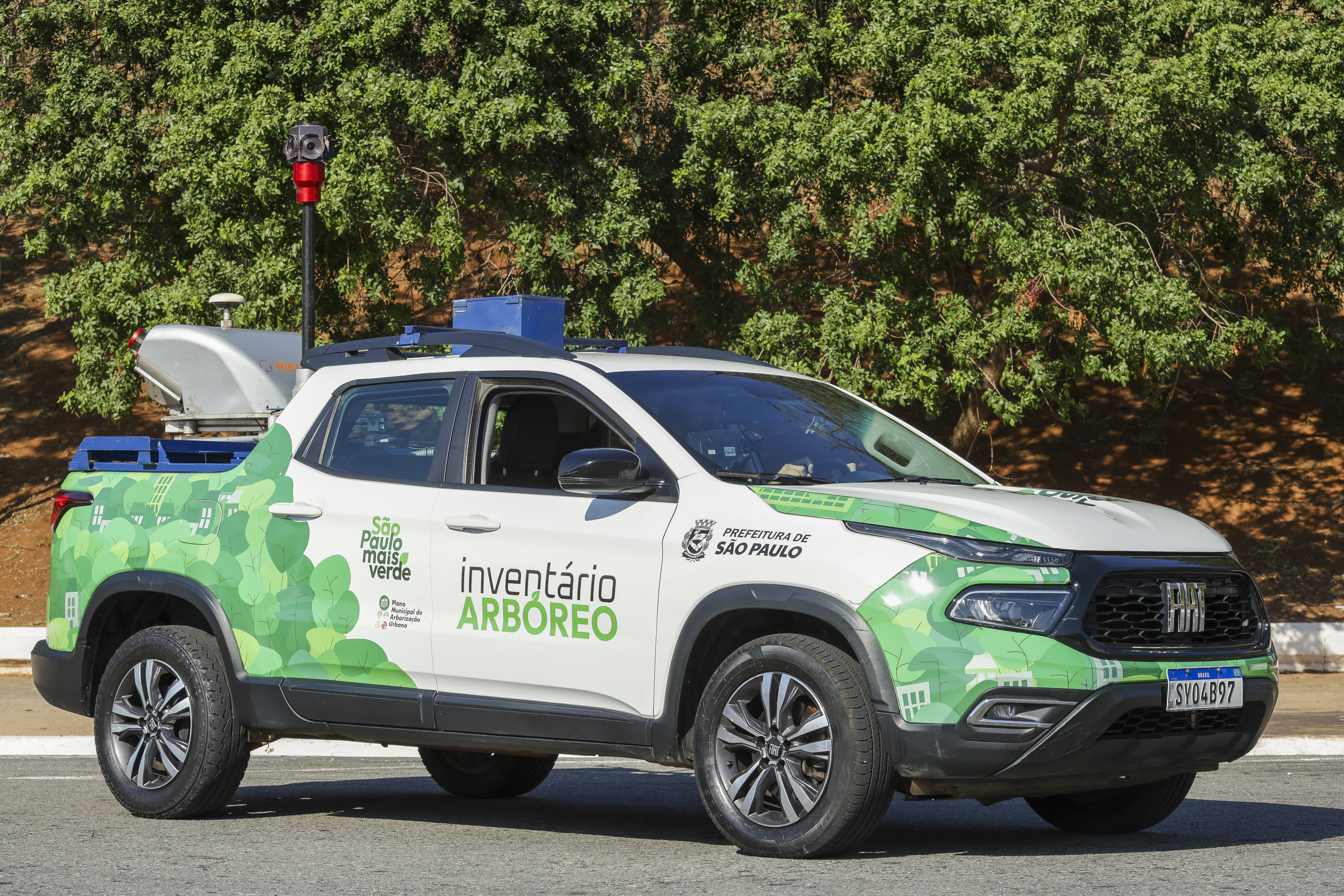 Veículo branco e verde identificado como "Inventário Arbóreo – Prefeitura de São Paulo" estacionado em via urbana. O carro possui equipamentos tecnológicos no teto e faz parte do programa "São Paulo Mais Verde".